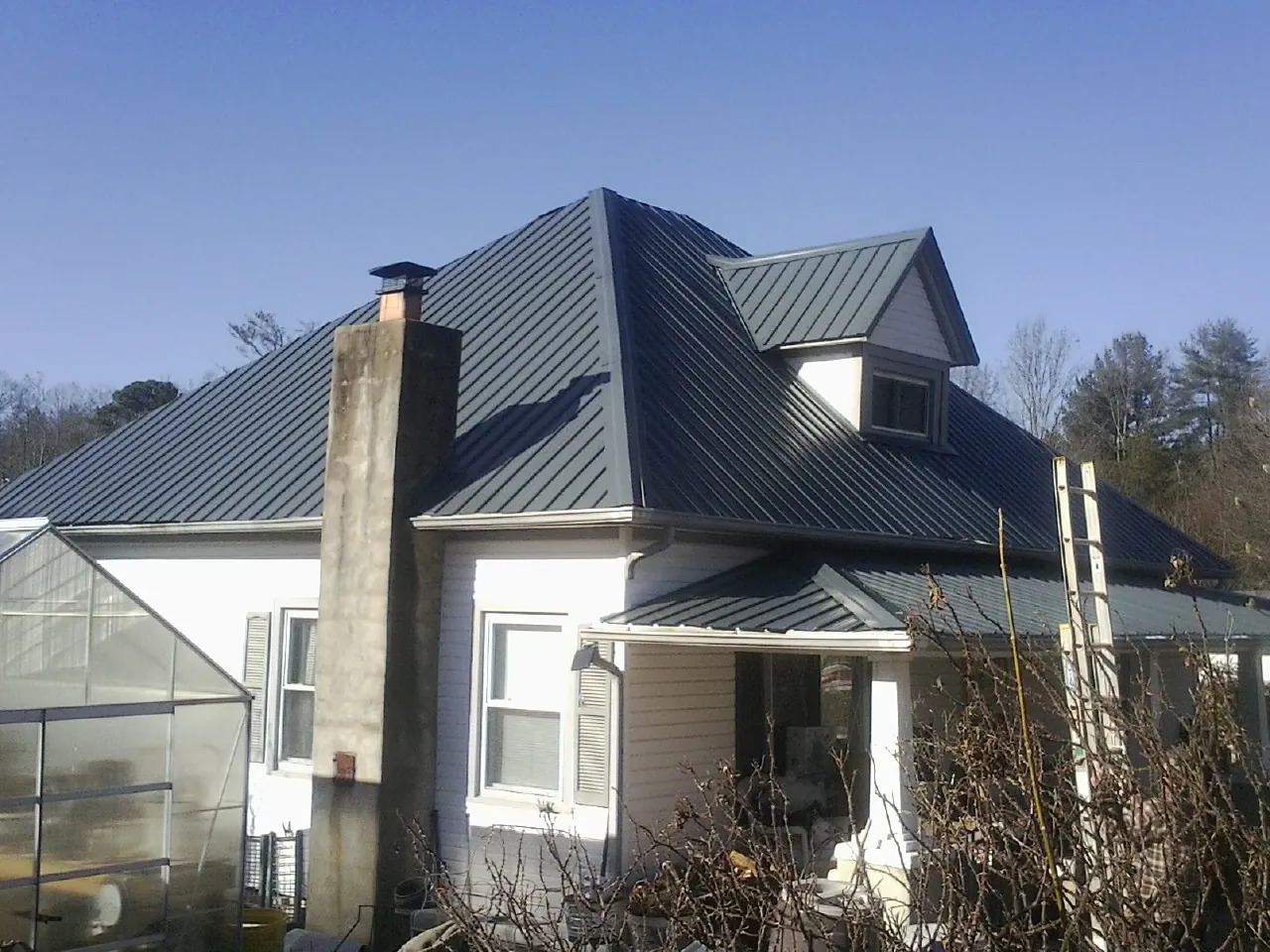 Dark blue standing seam metal roof on a white farmhouse with dormer — Slate & Tile Roof Repair by Roofing Brothers in Woodburn