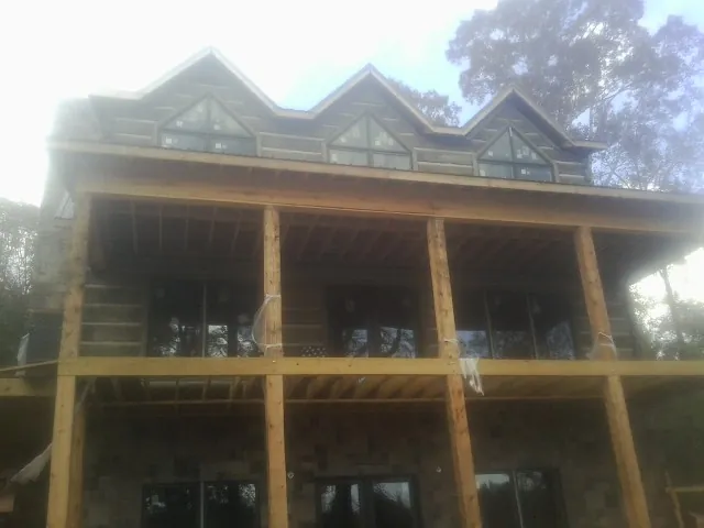 Dormers and porch framing on a large log home under construction — Roof Coating work by our crew in Woodburn